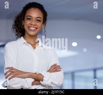 Bras croisés parce que je suis le patron. Photo d'une jeune femme d'affaires debout avec ses bras croisés dans un bureau au travail. Banque D'Images