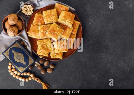 Savoureux baklava turque et Coran avec tasbih sur fond sombre Banque D'Images