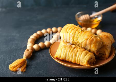 Savoureux baklava turque avec tasbih sur fond sombre Banque D'Images