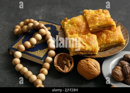 Savoureux baklava turque avec du Coran et du tasbih sur fond sombre Banque D'Images