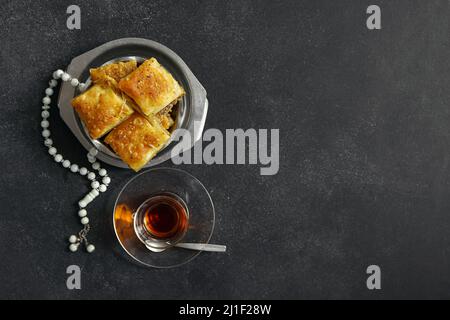 Savoureux baklava turque avec tasbih et thé sur fond sombre Banque D'Images