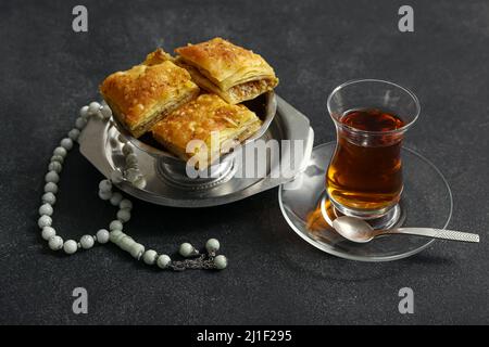 Savoureux baklava turque avec tasbih et thé sur fond sombre Banque D'Images