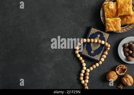 Savoureux baklava turque avec du Coran et du tasbih sur fond sombre Banque D'Images