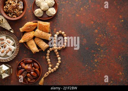 Savoureuses sucreries orientales avec tasbih sur fond de couleur Banque D'Images