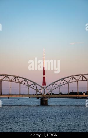 Riga, Lettonie - 15.08.2021 vue de la tour de radio et de télévision de Riga et du pont ferroviaire au coucher du soleil Banque D'Images