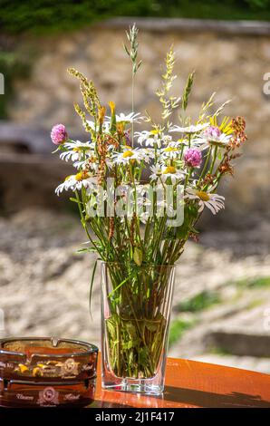 Encore vie de bouquet décoratif de fleurs dans un vase en verre avec cendrier sur une table, Château de Derneck près de Hayingen, Bade-Wurtemberg, Allemagne. Banque D'Images