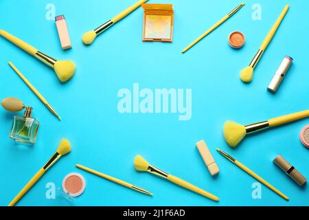 Cadre composé de brosses à maquillage et de produits cosmétiques sur fond bleu Banque D'Images