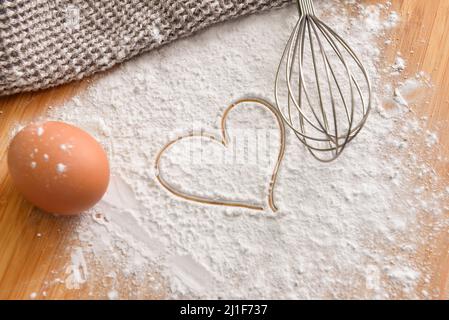 Œuf de poulet frais, farine avec coeur tiré et fouetter sur fond de bois Banque D'Images