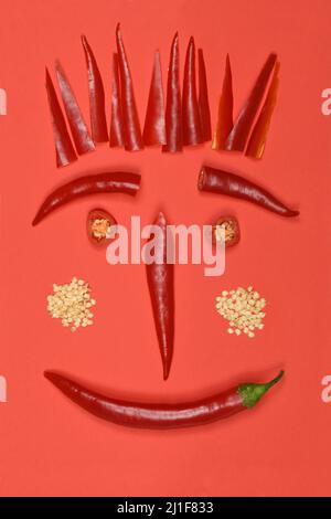 Piment rouge chaud sur un visage rouge et drôle fait de piment. Concept alimentaire créatif. Photo haute résolution. Profondeur de champ complète. Banque D'Images