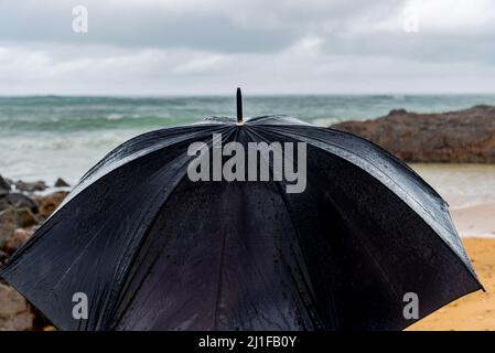 Parapluie noir humide contre la mer et le ciel.Salvador, Bahia, Brésil. Banque D'Images