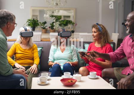 Des femmes et des hommes multiraciaux âgés avec des amis utilisant des micro-casques vr à la maison Banque D'Images