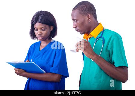 un médecin tenant un café, discutant d'un rapport médical sur la planchette à pince avec une infirmière à l'hôpital. Banque D'Images