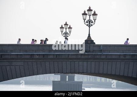 LONDRES, ROYAUME-UNI. 25th mars 2022. Piétons marchant sur le pont de Putney dans le sud-ouest de Londres sous le soleil brumeux une alerte élevée pour la pollution de l'air dans la capitale est émis par le maire Sadiq Khan pour Londres a apporté que les gens ont été invités à marcher, à vélo ou à utiliser les transports publics pour réduire la pollution de l'air. La qualité de l'air a empiré ces derniers jours avec des polluants en raison du temps chaud . Credit: amer ghazzal / Alamy Live News Banque D'Images