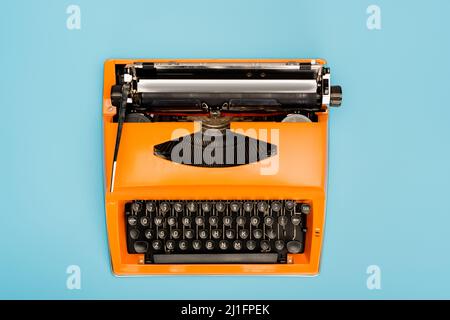 vue de dessus de la machine à écrire orange avec clavier noir isolé sur bleu Banque D'Images