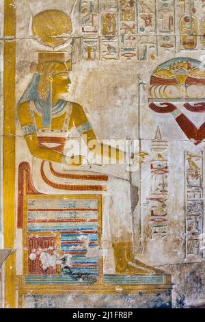 La déesse Isis, assise sur un trône et tenant un sceptre et un ankh, dans le Grand Temple d'Abydos, en Égypte Banque D'Images