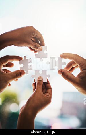 Chaque problème a une solution. Photo rognée d'hommes d'affaires qui se mêle à un puzzle dans un bureau moderne. Banque D'Images