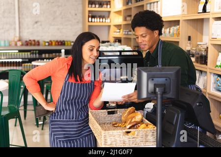 Jeunes collègues multiraciaux hommes et femmes discutant sur document au comptoir dans le café-restaurant. Unaltered, culture de café, les gens et l'occupation concep Banque D'Images
