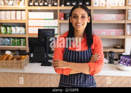 Portrait d'une jeune femme souriante et confiante avec les bras croisés portant un tablier au café-restaurant. Non modifié, culture du café, gens et l'occupation concep Banque D'Images