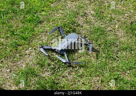 Un mini-drone s'est déployé sur une herbe avant le décollage. Un petit drone survole le parc pour prendre des vidéos et des photos. Livraison d'air à distance et Spy. Banque D'Images