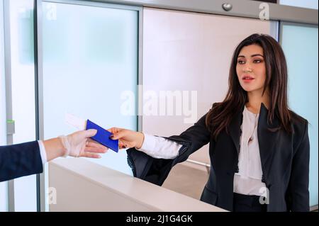 Belle fille à l'enregistrement de ses billets et à la réception de la carte d'embarquement par l'administrateur de l'aéroport Banque D'Images