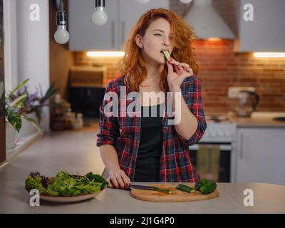 Bonne souriante mignonne femme de cuisiner des légumes frais et sains salade de légumes à la maison dans la cuisine et d'essayer une nouvelle recette. Nutrition pour l'amincissement, perte de poids Recettes alimentaires concept Banque D'Images