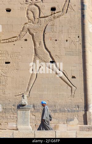 Egyptien local marchant en face du premier pylône du Temple d'Isis à philae où Ptolémée XII Neos Dionysos est représenté en train de mordre ses ennemis Banque D'Images