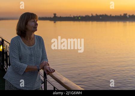 Femme regardant le Nil depuis un bateau de croisière au coucher du soleil Banque D'Images