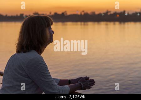 Femme regardant le Nil depuis un bateau de croisière au coucher du soleil Banque D'Images