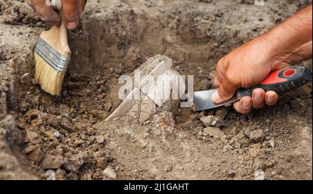 Des fouilles archéologiques, des archéologues travaillent, creusent un antique artefact en argile avec des outils spéciaux dans le sol Banque D'Images