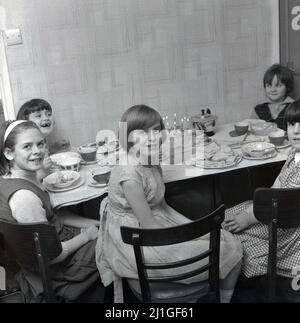 1960s, historique, fête de thé d'anniversaire, cinq jeunes filles s'asseyaient autour d'une table de cuisine, bougies s'allumant sur le gâteau, Manchester, Angleterre, Royaume-Uni. Banque D'Images