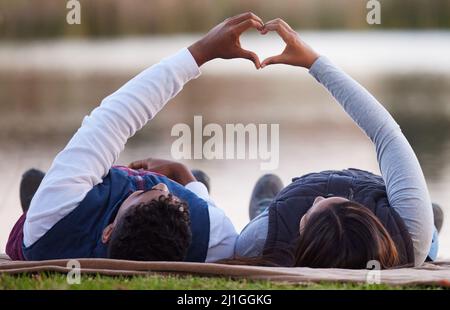 Mon cœur est complet avec vous. Photo d'un couple créant une forme de coeur avec leurs mains pendant un voyage de camping. Banque D'Images