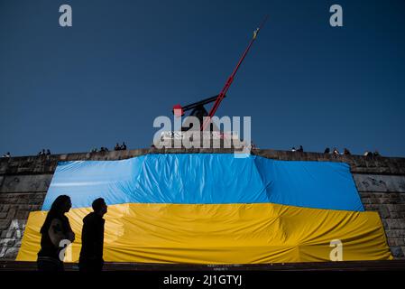 Prague, République tchèque. 25th mars 2022. Un couple passe devant un grand drapeau ukrainien placé dans le parc de Letna sous la statue du pendule à Prague. Plus de 250000 000 réfugiés d'Ukraine sont arrivés en République tchèque depuis le début de l'invasion russe de l'Ukraine. Crédit : SOPA Images Limited/Alamy Live News Banque D'Images