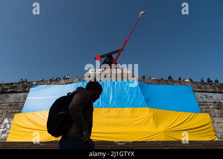 Prague, République tchèque. 25th mars 2022. Un homme passe devant un grand drapeau ukrainien placé dans le parc de Letna sous la statue du pendule à Prague. Plus de 250000 000 réfugiés d'Ukraine sont arrivés en République tchèque depuis le début de l'invasion russe de l'Ukraine. Crédit : SOPA Images Limited/Alamy Live News Banque D'Images