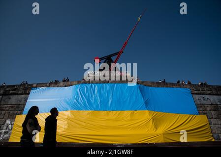 Prague, République tchèque. 25th mars 2022. Un couple passe devant un grand drapeau ukrainien placé dans le parc de Letna sous la statue du pendule à Prague. Plus de 250000 000 réfugiés d'Ukraine sont arrivés en République tchèque depuis le début de l'invasion russe de l'Ukraine. (Photo de Tomas Tkachik/SOPA Images/Sipa USA) crédit: SIPA USA/Alay Live News Banque D'Images