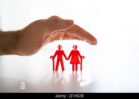 Figurines de découpe pour couple senior de protection des mains sur le bureau blanc Banque D'Images