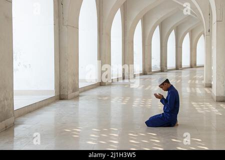 Dhaka, Bangladesh. 25th mars 2022. Un enfant prie à la mosquée nationale Baitul Mukarram à Dhaka, au Bangladesh. La mosquée nationale du Bangladesh, connue sous le nom de Baitul Mukarram ou la Maison Sainte en anglais, est l'une des 10 plus grandes mosquées au monde et peut accueillir jusqu'à 40 000 personnes, y compris dans l'espace ouvert extérieur. La mosquée possède plusieurs caractéristiques architecturales modernes tout en préservant les principes traditionnels de l'architecture moghole qui domine depuis un certain temps dans le sous-continent indien. Crédit : ZUMA Press, Inc./Alay Live News Banque D'Images