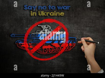 Une fille dessine un réservoir sur un tableau de craie avec le texte dire non aux guerres en Ukraine Banque D'Images