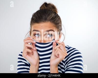 Il est temps de faire comme une tortue et de se cacher. Photo d'une belle jeune femme utilisant sa chemise pour couvrir sa bouche et son nez. Banque D'Images