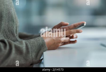 La technologie au bout des doigts. Image rognée d'une femme d'affaires méconnue utilisant son téléphone portable au bureau. Banque D'Images