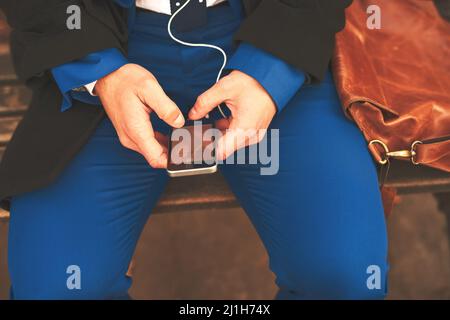 La musique vous met dans la bonne humeur. Prise de vue d'un homme méconnaissable qui écoute de la musique tout en étant assis sur un banc à l'extérieur le matin. Banque D'Images