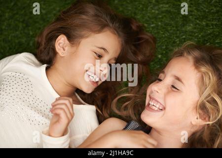 Un pur délice pour l'enfance. Coupe courte de deux petites filles allongées sur le dos à l'extérieur. Banque D'Images