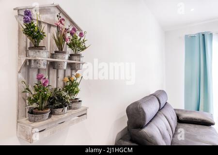 Étagère décorative en bois avec plantes artificielles dans des pots à côté d'un canapé en cuir Banque D'Images