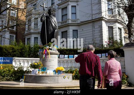 Londres, Royaume-Uni. 25th mars 2022. Deux personnes âgées sont vues debout devant la statue de Saint Volodymyr. La statue de Saint Volodymyr fut érigée pour marquer le millénaire, en 1988, de la Christianisation de l'Ukraine-Russie. Il a été fait par le sculpteur ukrainien canadien Leo mol. Les gens ont posé des tournesols autour de la statue comme symbole pour soutenir l'Ukraine dans la guerre Russie-Ukraine. Crédit : SOPA Images Limited/Alamy Live News Banque D'Images