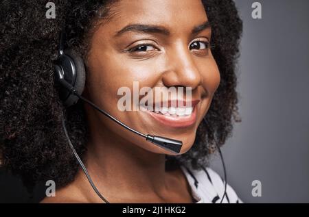 Mon client est toujours le premier. Portrait en studio d'un jeune opérateur téléphonique confiant posé sur un fond gris. Banque D'Images