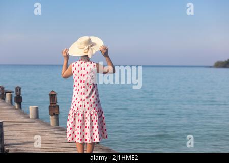 Femme d'âge moyen se reposant sur une jetée en bois en vacances à koh Kood, Thaïlande. Banque D'Images