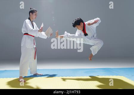 Un jeune entraîneur a enseigné au petit garçon d'apprendre le tae kwon do Banque D'Images