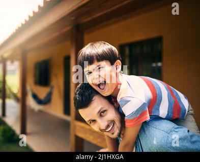 Les deux d'entre nous ont un tel plaisir. Portrait court d'un jeune père affectueux qui soutient son petit fils en se tenant dans leur arrière-cour Banque D'Images