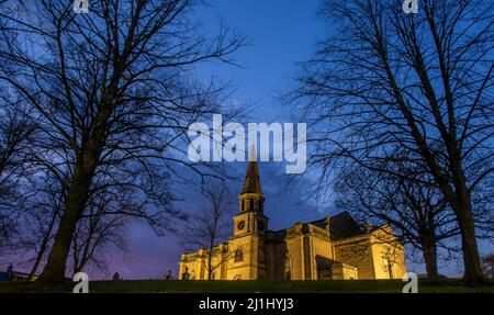 Melrose, Royaume-Uni. 25th mars 2022. 25th mars 2022 climat d'Écosse, vue en soirée de l'église paroissiale illuminée de Melrose. Ce bâtiment a été construit entre 1808 et 1810, dédié à St Cuthbert et il a remplacé l'abbaye comme lieu de culte. Un incendie en 1908 a détruit une grande partie du bâtiment et un nouveau kirk a été construit qui a incorporé la tour et la flèche de son prédécesseur. Le monument commémoratif de guerre situé en bordure du terrain de kirk a été érigé à la mémoire des hommes de Melrose qui sont morts pendant la première Guerre mondiale. Après la Seconde Guerre mondiale, les noms de ceux qui sont morts dans ce conflit ont été ajoutés. Crédit: p Banque D'Images