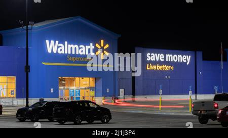 L'avant d'un supermarché Walmart est photographié tard dans la nuit lorsqu'une voiture passe. Banque D'Images