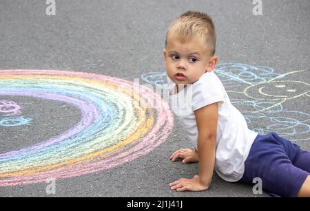 L'enfant dessine avec de la craie sur la chaussée. Mise au point sélective Banque D'Images